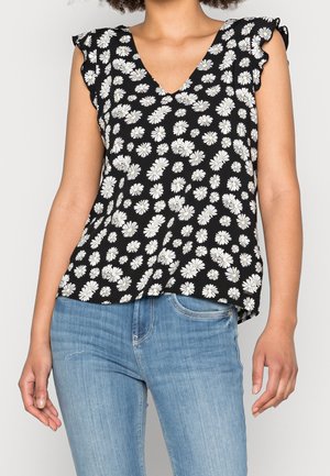 Haut noir sans manches à imprimé marguerites blanches avec un col en V, doté d'épaules à volants et d'une coupe ample, associé à un jean bleu clair.