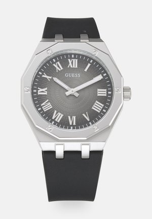 Achtseitige Uhr mit einem grauen strukturierten Zifferblatt, silbernen römischen Ziffern und silbernen Akzenten. Verfügt über ein schwarzes Gummiband und eine Krone.