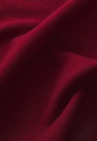Deep red, textured fabric with a soft, fine weave. The material drapes smoothly, showing subtle variations in shade and light.