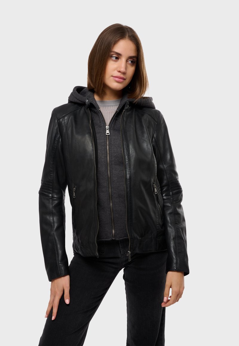 Crna kožna jakna s prilagođenim dizajnom, s patentnim zatvaračem na džepovima i ispod nje sivi dukserica s kapuljačom. Ima teksturirane rukave i glatku završnicu.