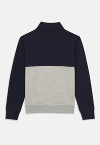 Genser med marineblå overdel og lys grå underdel. Har krage, lange ermer og ribbestrikket kant. Glatt bomullsblandingsmateriale.