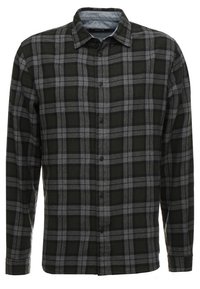 Camisa de franela a cuadros en blanco y negro, con cuello abotonado, mangas largas y una textura suave. Botones centrados en el frente y dobladillo recto.