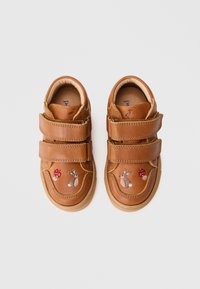 Zapatos de piel marrón con dos correas de velcro, con conejitos y setas bordadas en la parte delantera, suela de goma y forma redondeada.