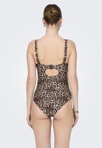 Jednodijelni kupaćI kostim s motivom leoparda, s podesivim naramenicama i detaljem u obliku ključanice na leđima, koji se odlikuje glatkom teksturom i visokim izrezom na nogavicama.