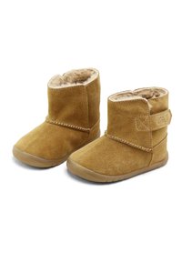 Botas de tobillo de ante color beige con un suave forro de piel y un cierre de velcro. Presentan una punta redondeada y una suela flexible de goma.