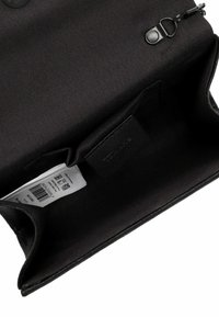 Must musta kotike, millel on tõmblukk, sile tekstuur ja väike nahklabel sees. Sisaldab tootemärki ja hooldusjuhiseid.