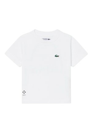 T-shirt bianca a maniche corte Lacoste Sport con logo coccodrillo verde sul petto sinistro e piccolo testo nero vicino all'orlo inferiore sinistro.