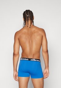 Blaue Baumwoll-Boxershorts mit einem kontrastierenden schwarzen Bund, der den Markennamen trägt. Die Ansicht von hinten hebt die glatte Textur hervor.