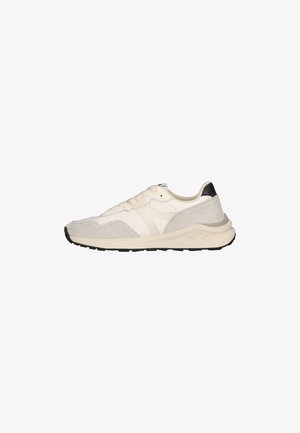 Lichtbeige en witte sneaker met suède details, veters aan de voorkant, dikke zool en zwarte hielaccent, getoond vanaf de buitenkant op een witte achtergrond.