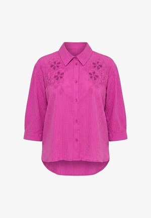 Blouse rose vif à rayures verticales, broderie florale découpée sur les épaules, boutons sur le devant, manches 3/4 et ourlet arrondi plus long à l’arrière.