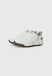 Baskets de sport blanches avec des accents gris, tige texturée, col rembourré et un logo S noir. Semelle extérieure avec crampons orange pour une meilleure adhérence.
