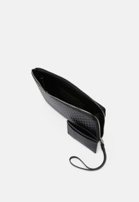 Pasta de couro preto com um padrão de diamante texturizado, fecho de zip, slots para cartões no interior e alça para o pulso.