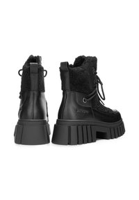 Botines negros con exterior de cuero texturizado, cuello de piel sintética y suelas gruesas de caucho ranurado para una mayor tracción.