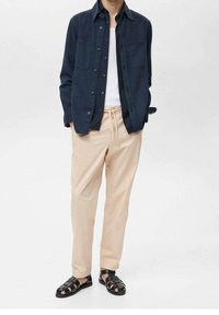 Námořnická košile na knoflíky se dvěma kapsami na prsou, béžové kalhoty s elastickým pasem a černé páskové sandály. Jednoduchý, volný střih.