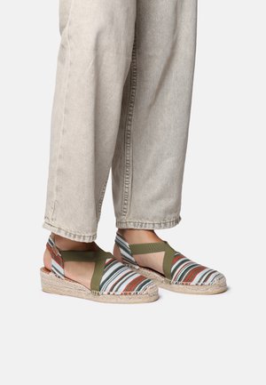 Striped espadrille sandals with a wedge heel, featuring green and red accents, canvas material, and crisscross straps.