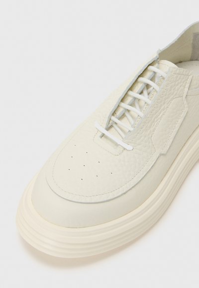 Hvide lædersneakers med struktureret overdel, rund tå og en tykk gummisål. Har tonalt syning og traditionel snørlukning.