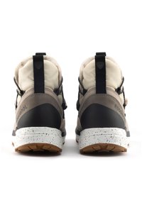 Las botas de senderismo en marrón y beige cuentan con un cuello acolchado, detalles texturizados en negro, una entresuela blanca con manchas y una suela de goma con un patrón de agarre.