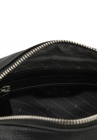 Interior de bolso de cuero negro con un bolsillo con cremallera, con una tela forrada con sutiles rayas diagonales. Detalles en cremallera plateada.