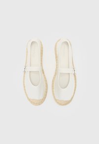 Hvide canvas espadrilles med en vævet jutesål, rund tå og en dekorativ rem med en sølvspænde. Minimalistisk design med naturlig tekstur.