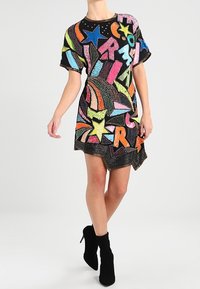 Kortärmad klänning med svart bas och livfulla, flerfärgade stjärn- och bokstavsdesigns. Den har en texturerad yta och en något asymmetrisk fåll.