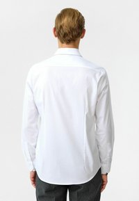 Witte blouse met lange mouwen en een klassieke kraag, met een gladde textuur en knoopmanchetten, ontworpen voor een getailleerde pasvorm.