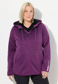 Fleecejacke mit einem lila gesprenkelten Muster, Reißverschluss vorne und Kapuze. Verfügt über ein schwarzes Fleece-Futter und reflektierende Akzente an den Ärmeln.