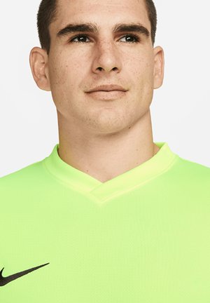 Maglia sportiva verde Nike con scollatura a V e tessuto testurizzato. Presenta un logo Nike swoosh nero sul lato sinistro.