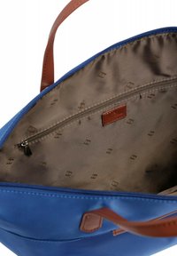 Borsa a tracolla blu con dettagli in pelle marrone, chiusura con zip e interno foderato con un motivo sottile. Tasca interna visibile.