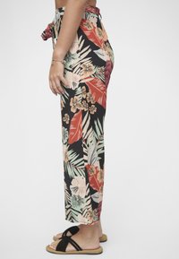 Vide bukser med blomstertrykk har svart bakgrunn med røde, grønne og beige detaljer, knytebelte i livet og pustende stoff.