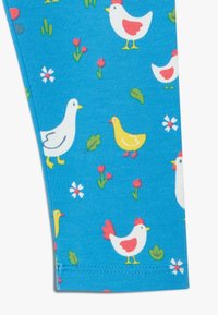 Tela azul con un patrón juguetón de varias gallinas y patos, junto con flores y hojas, en colores vibrantes.