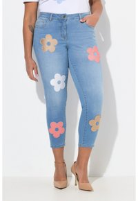 Vaqueros capri de mezclilla azul claro con aplicaciones de flores en rosa, blanco y marrón en las piernas. Incluyen una cinturilla estándar y bolsillos.