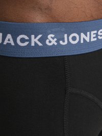 Boxer slip neri con una cintura elastica blu che riporta il testo "JACK & JONES" in bianco. Il tessuto sembra liscio e aderente.