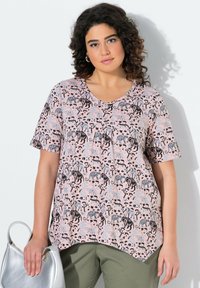 Camiseta de manga corta en tono rosa claro con escote en V, con un estampado repetido de animales y árboles en negro y gris. Dobladillo curvo, tejido suave.