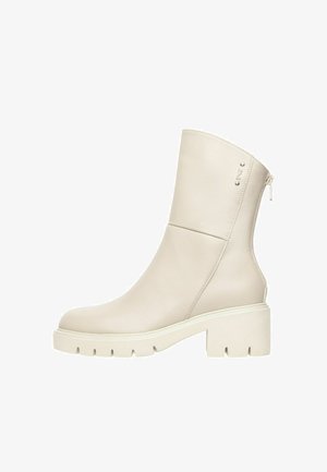 Off-white leren midkuitlaars met grove zool, blokhak, rits aan de zijkant en klein metalen logo vlak bij de bovenrand.