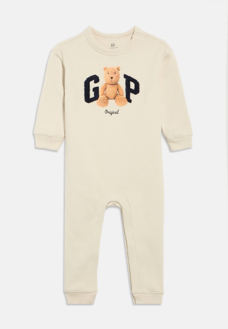 Béžové bavlnené body s dlhými rukávmi, so vyšívaným medveďom a nápisom "GAP" v námorníckej modrej. Zapínanie na gombíky na ramene, elastické manžety.