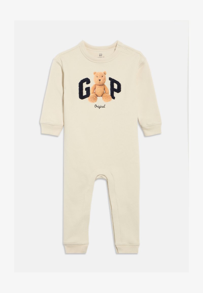 Béžové bavlnené body s dlhými rukávmi, so vyšívaným medveďom a nápisom "GAP" v námorníckej modrej. Zapínanie na gombíky na ramene, elastické manžety.
