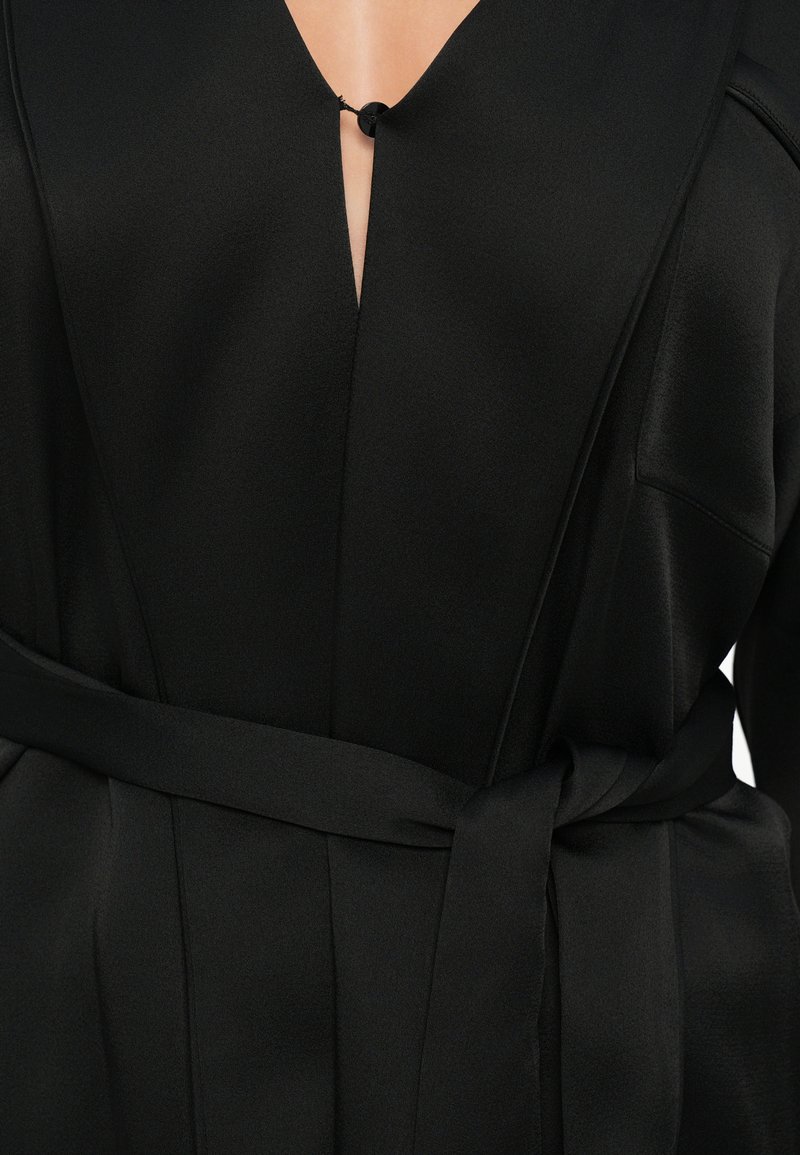 Schwarzes Satin-Kleid mit V-Ausschnitt, dekorativem Knopfverschluss und Taillengürtel. Glatte Textur mit subtiler Glanz und seitlichem Taschen.