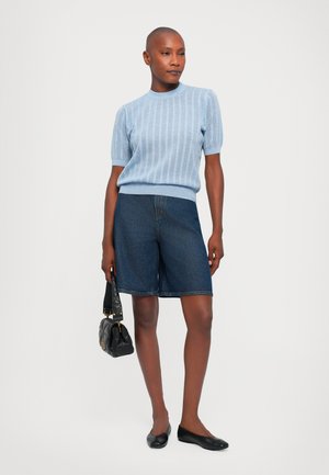 Light blue knitted short-sleeve sweater, dark denim bermuda shorts, black flats, and a small black handbag. Smooth textures and casual design.