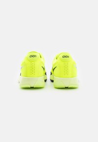 Neon gule treningssko med svarte detaljer, mesh-overdel, teksturert såle og karakteristisk "001" merke på hælen.