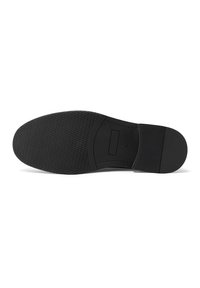 Suola di una scarpa in gomma nera con una superficie testurizzata, modelli circolari e un tacco piatto. Presenta un bordo liscio e un branding minimale.