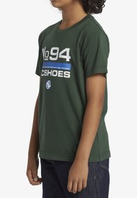 Zelené bavlněné tričko s kulatým výstřihem, krátkými rukávy a potiskem v bílé a modré barvě, se slovy "No 94" a "DC Shoes".