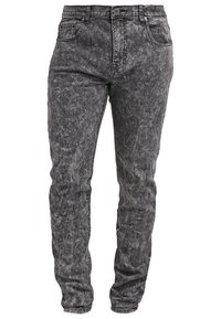 Odstupněné černé džíny s distressed texturou, designem s pěti kapsami a poutky na opasek. Slim fit s viditelným šitím a jemnými detaily opotřebení.