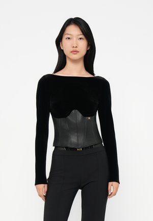 Black long-sleeve top combining soft velvet and structured leather corset. Features a curved bust line with a gold logo accent. Fitted design.