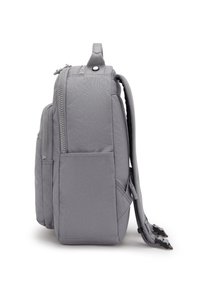 Sac à dos en tissu gris de forme rectangulaire, doté de zips et de poches latérales, avec des bretelles ajustables et un design structuré.