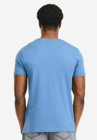 Kurzärmeliges T-Shirt aus hellblauem Stoff mit rundem Ausschnitt und regulärer Passform, glatter Textur und minimalen Designdetails.
