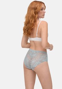 Bragas de alta cintura en encaje azul claro con patrones florales, que presentan una textura suave y bordes con forma de ondas, acompañadas de un sujetador blanco.