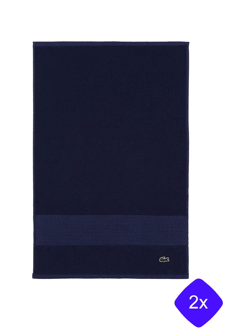 Toalla de baño azul marino con una banda texturizada a rayas y un pequeño logo verde bordado en la esquina. Material de algodón suave y absorbente.