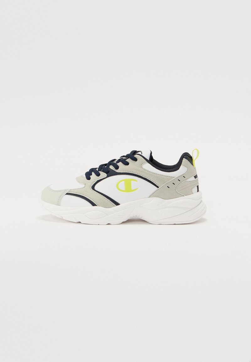 Valged, hallid ja tummsinised tenis kingad, millel on paks disain, tekstuuriga paneelid ja kollane logo aktsent külgedel.