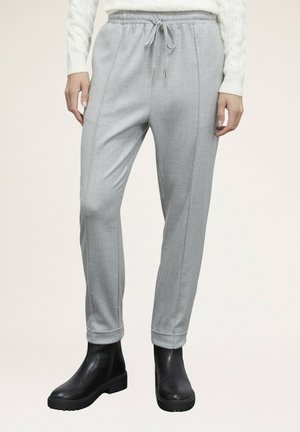 Grijze op maat gemaakte broek met een trekkoord in de taille, voorzien van twee verticale naden en een omslagzoom, gecombineerd met zwarte enkellaarsjes.