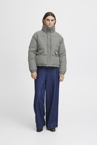 Puffjakke i mønstret stoff med høy krage og glidelås, kombinert med vide denimbukser. Teksturert overflate med flere farger.